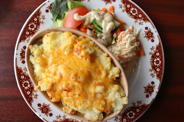 a shepherd\'s pie topped with cheese, served with salad
