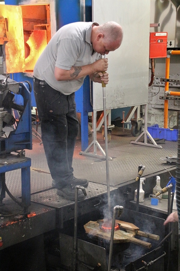 A man blowing glass in a cast iron mold