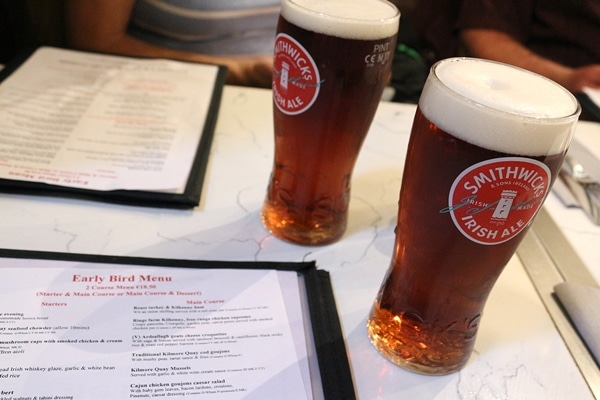 2 glasses of Irish ale on a table with restaurant menus