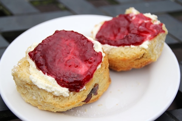 a halved scone topped with clotted cream and jam