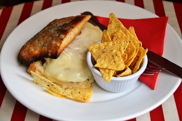 a sandwich on a plate with chips on the side