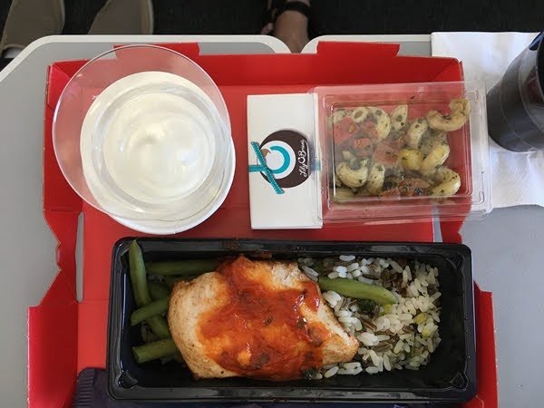 A tray of food on an airplane tray table