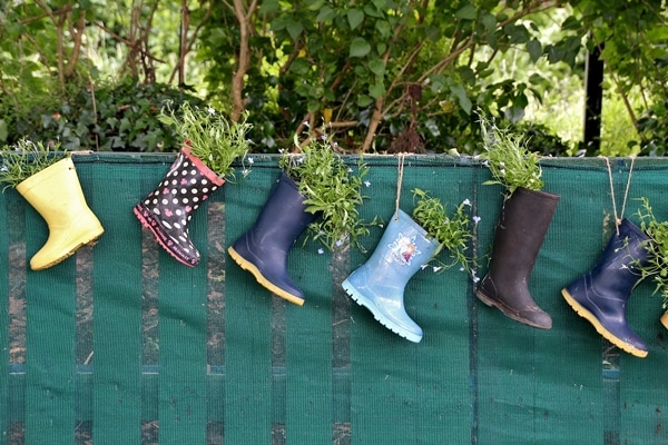 rain boots filled with flowers hanging from a fence