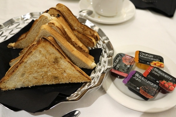 toast on a platter with small packages of jam on the side