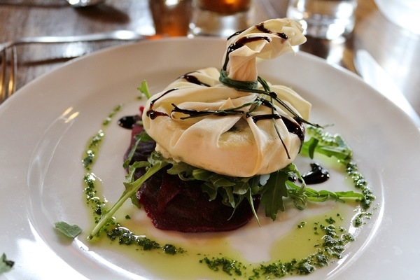 a dough purse on a plate with green sauce