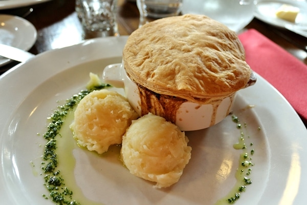 a pot pie with scoops of mashed potatoes on the side