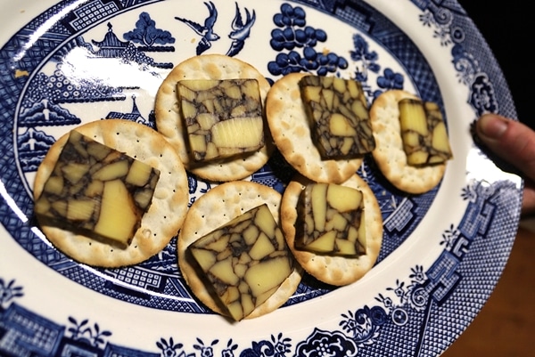 wine infused cheese on top of crackers on a platter