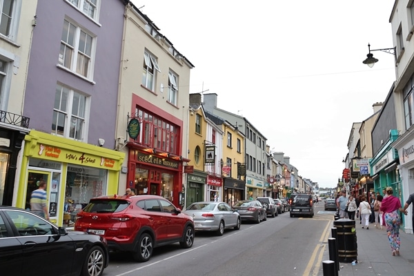 A narrow city street with cars parked on the side