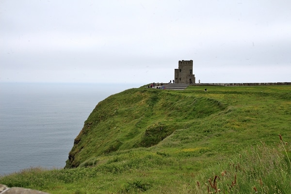 a stone building on top of a grassy hill by the sea