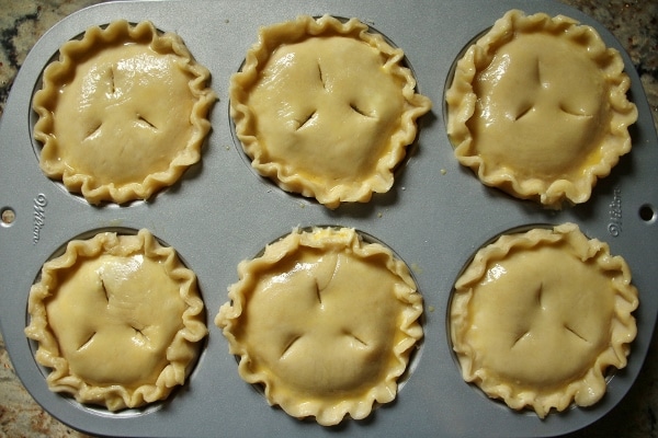 6 small pies assembled in a jumbo muffin pan, brushed with egg wash