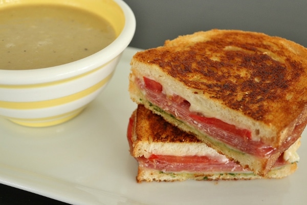 A grilled cheese with salami, tomato, and pesto