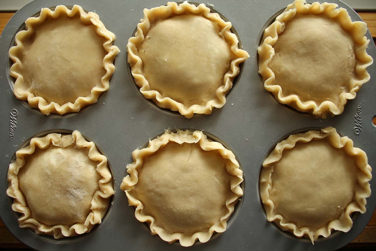 6 small unbaked pies assembled in a jumbo muffin pan.
