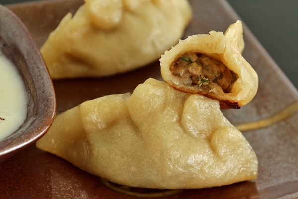 A close up manti dumplings, with a bite taken out of one