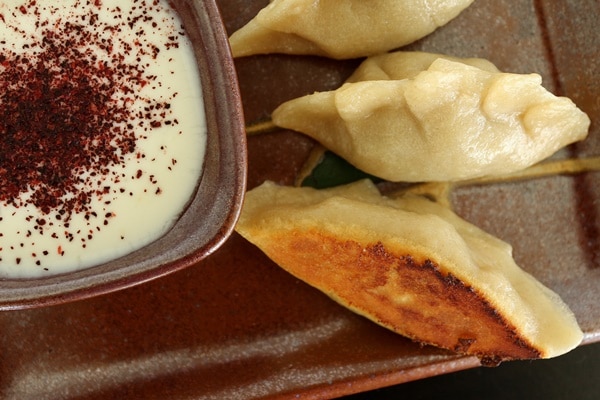 A close up of a plate of pan-fried manti dumplings