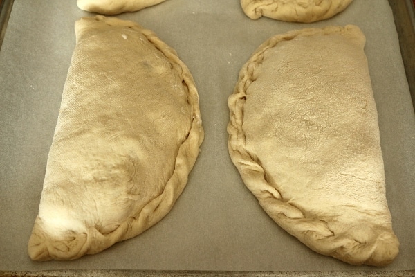 2 unbaked calzones on a baking sheet