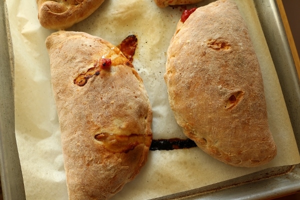A close up of baked calzones on a baking sheet