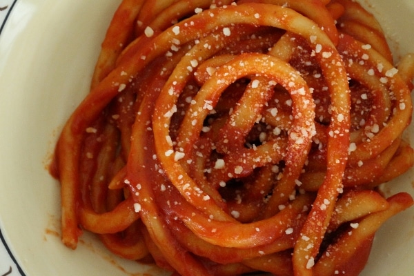 Hand-rolled pici pasta in tomato sauce, topped with grated cheese