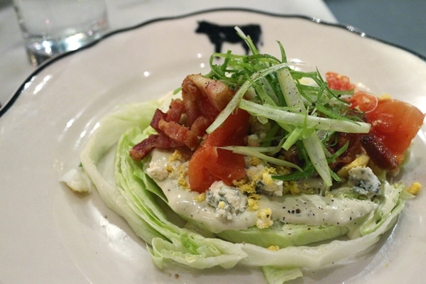 slice of iceberg lettuce topped with bacon and blue cheese