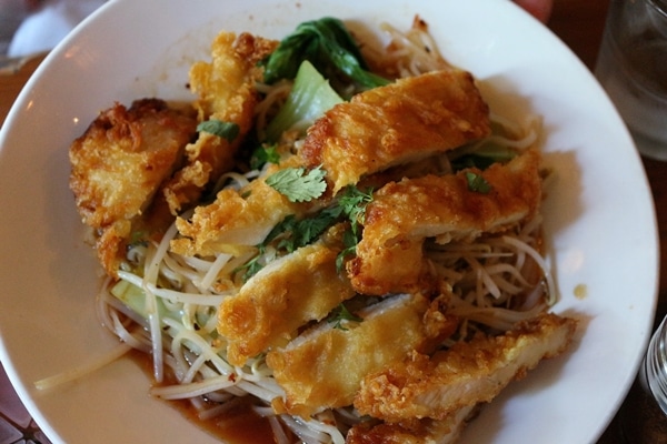 a plate of noodles topped with sliced fried chicken breast