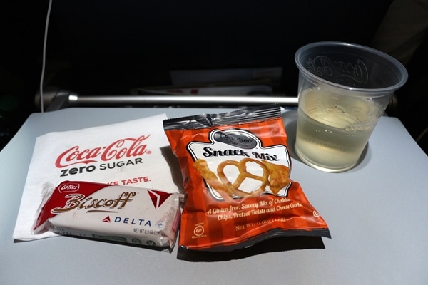 airplane snacks and a drink on a tray table