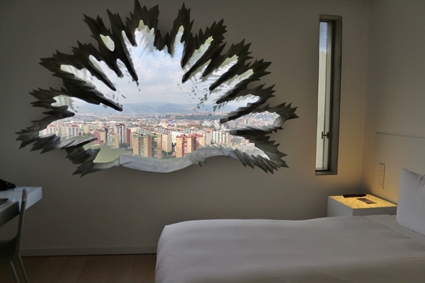 A hotel bedroom with a palm shaped window