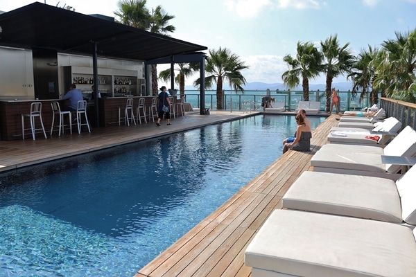 a rooftop hotel pool with lounge chairs and palm trees