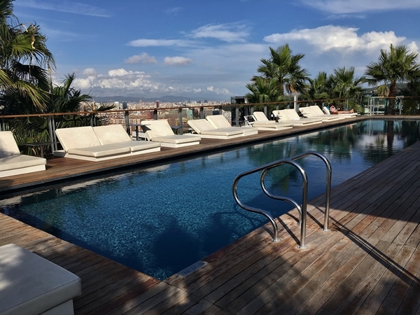 a rooftop pool with lounge chairs overlooking Barcelona