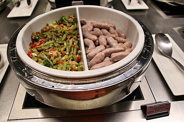 vegetables and small sausages on a buffet line