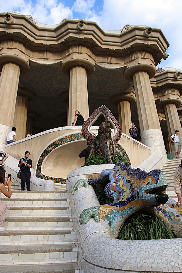 a mosaic lizard statue in front of a building with columns