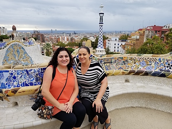 2 women sitting on a bench posing for the camera