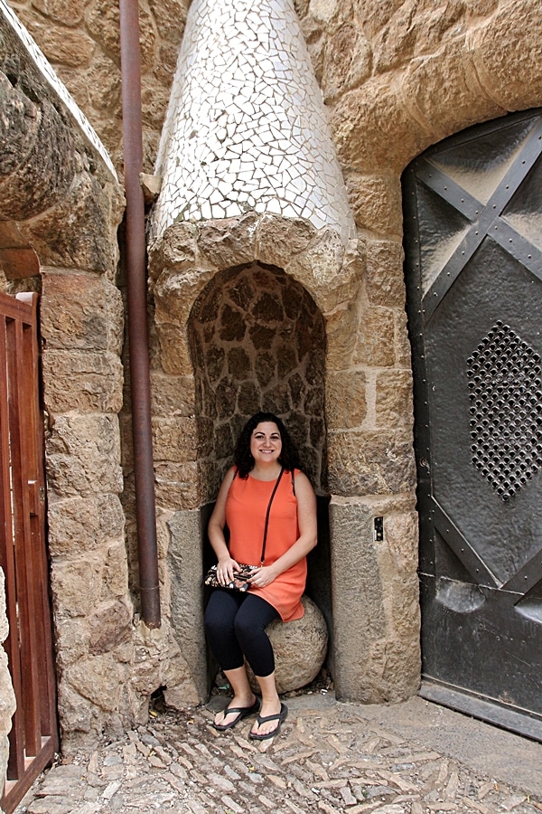 A person sitting in front of a stone building in Park Güell