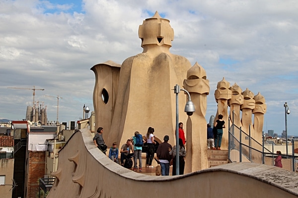 people on the rooftop of Casa Milà with Sagrada Familia in the distance