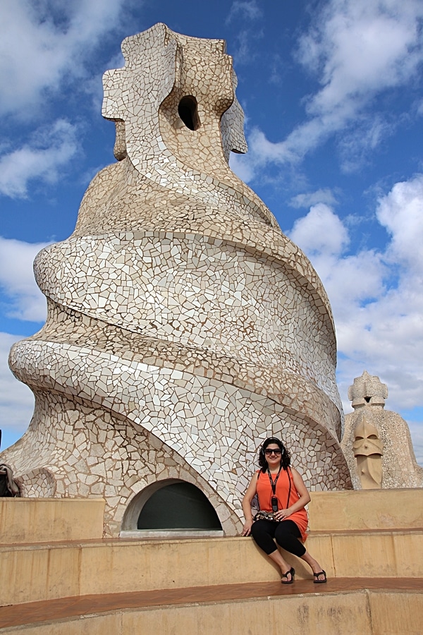 a woman sitting in front of a large mosaic rooftop chimney