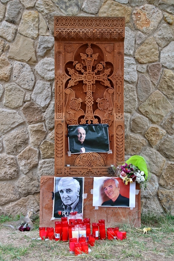 close up of a stone cross with pictures of a man taped to the front