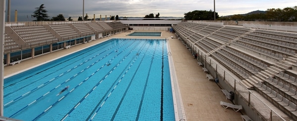 an outdoor Olympic swimming pool with seating on either side