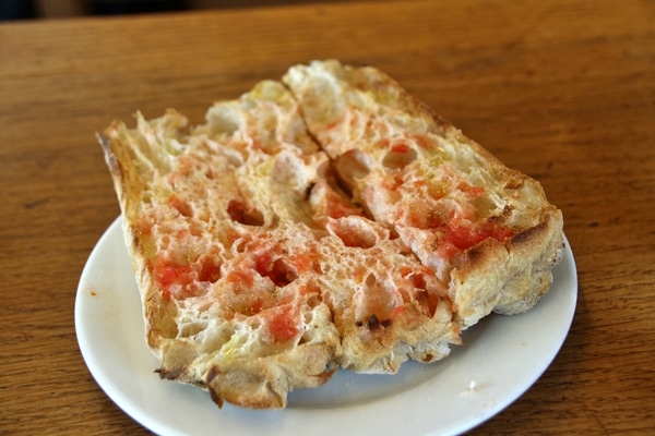 A piece of bread rubbed with tomato on a plate