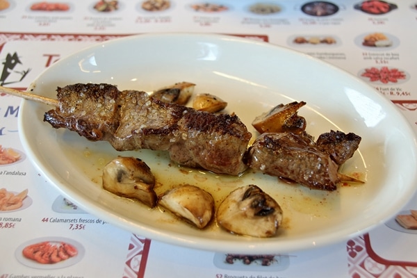 a skewer of beef with mushrooms on a plate