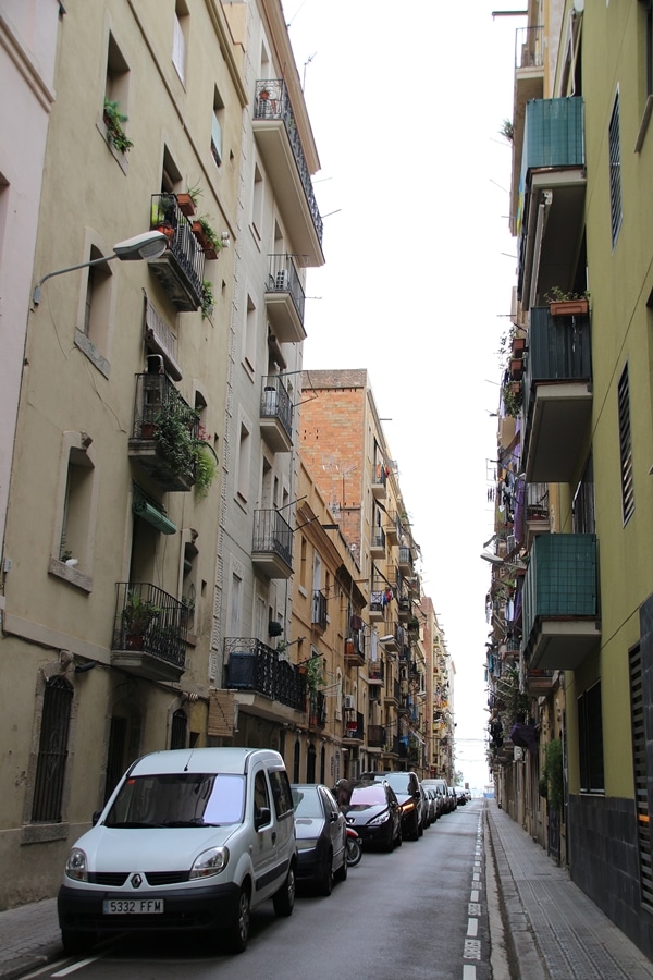 A narrow city street with cars parked on the side of a road