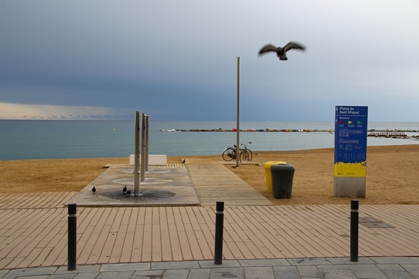 an empty beach with a storm in the distance