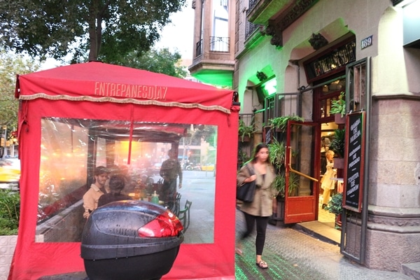 a red tent covering restaurant seating on a sidewalk