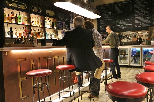 2 people sitting on bar stools in a small restaurant