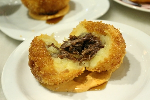 a fried potato ball cut in half to show meat filling