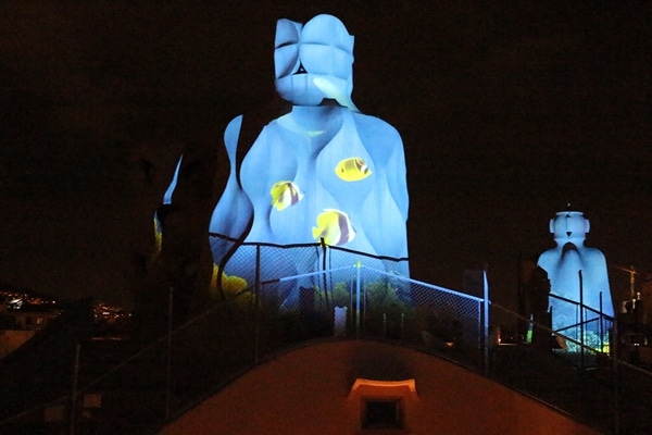 illumination of fish in the ocean on the side of a stone chimney at night