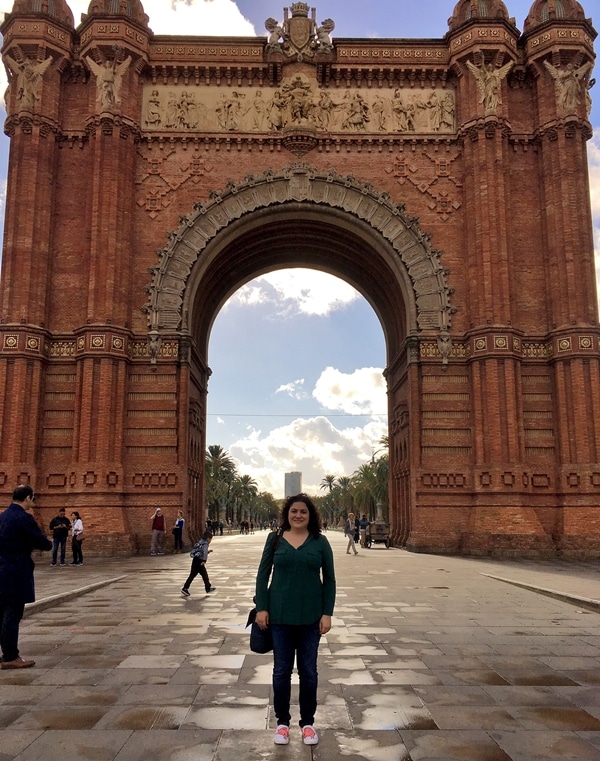 A person standing in front of the Arc de Triomf