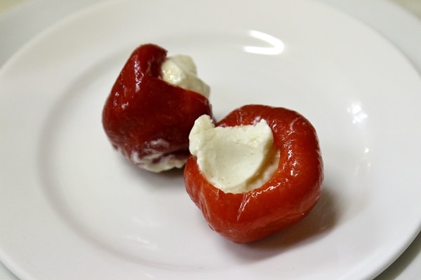 2 small goat cheese stuffed peppers on a white plate