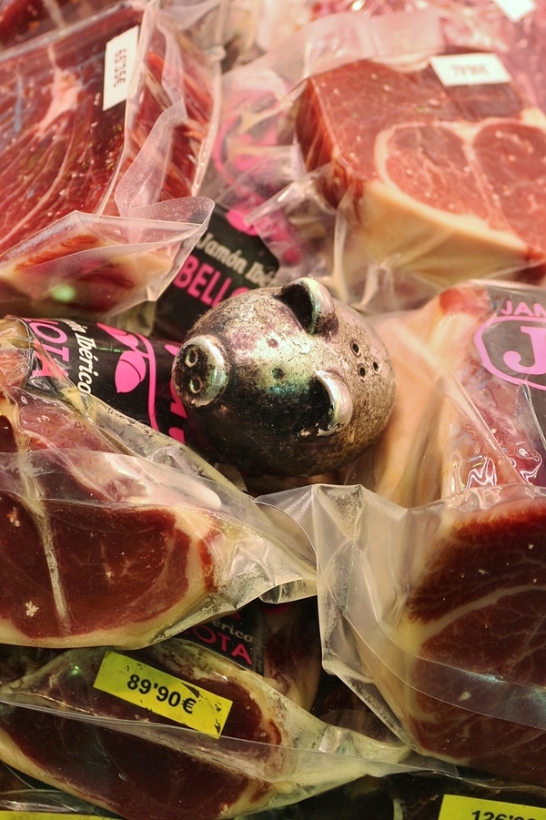 closeup of a small metal pig figurine in a meat display