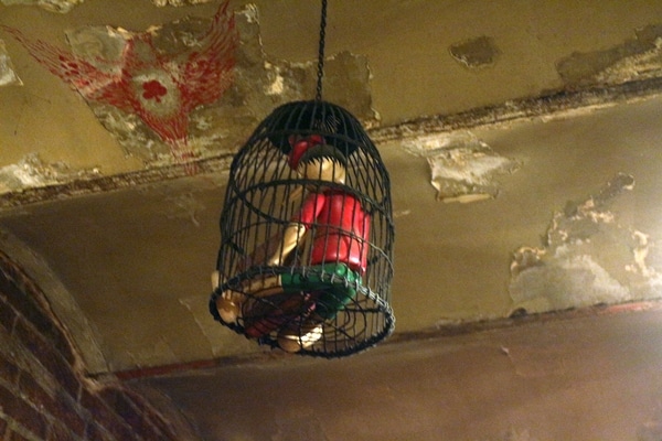 A close up of a cage holding a wooden doll