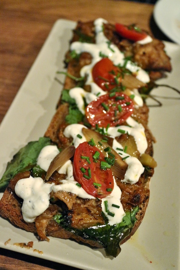 closeup of an open-faced sandwich with creamy sauce and cherry tomatoes