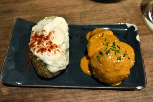 a plate of whole potatoes topped with white and red sauces