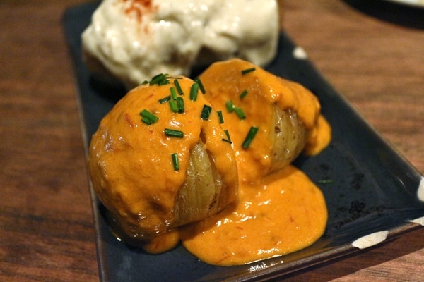 A close up of a potato topped with a reddish sauce